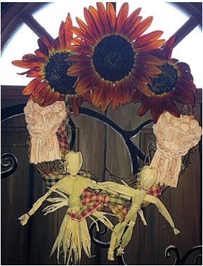 Finished Lughnasadh altar wreath with sunflowers, corn dollies, and clay wheat on a grapevine base